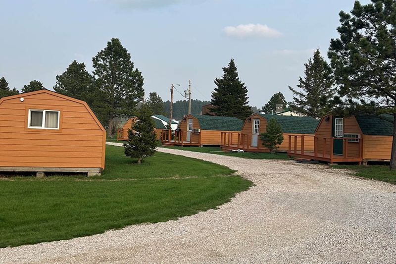 Row of camping cabins along the gravel drive at Custer Crossing Family Campground
