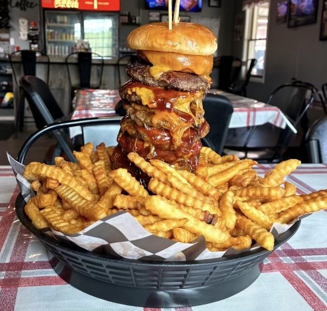 Custer's Last Burger Challenge with stacked burger patties and fries at Custer's Last Meal
